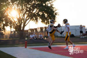 Two boys football players compete during a game on an outdoor field.