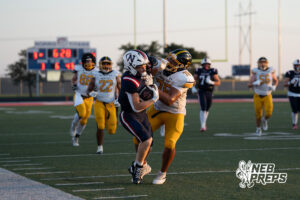 Two boys football players compete during a game on an outdoor field.