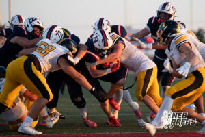Two boys football players compete during a game on an outdoor field.
