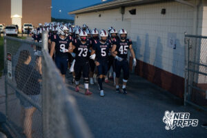 Boys football players compete during a game on an outdoor field.