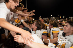 Players celebrate during a game on an outdoor field.