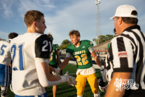 Two boys football players compete during a game on an outdoor field.