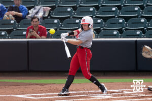 Jesse Farrell swings at a pitch in a college softball game.