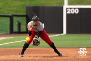 A Nebraska player fields a ground ball during warm-ups in a college softball game.