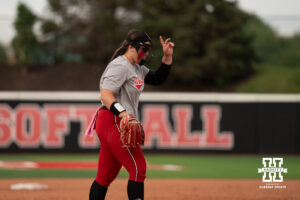 Alexis Jensen signals to her teammates from the circle in a college softball game.