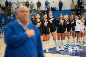 Marian players stand for the national anthem in a high school volleyball match.