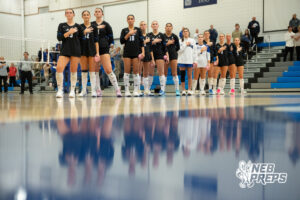 Marian players stand for the national anthem in a high school volleyball match.