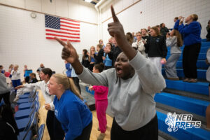 Fans cheer from the student section in a high school volleyball match.