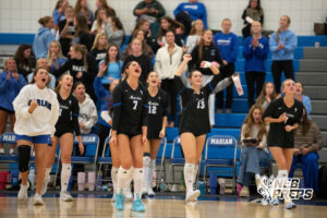 Trinity Rocha and Jordan Frink celebrate a point with teammates in a high school volleyball match.