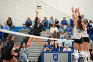 Taylor McLeay tips the ball over the Papillion-LaVista South block in a high school volleyball match.