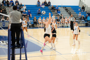 Maddox Graves jumps to play the ball near the net in a high school volleyball match.