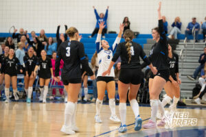 Teagan Menicucci celebrates a point with teammates in a high school volleyball match.