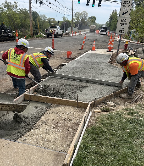 Workers install sidewalk at Paddock Avenue