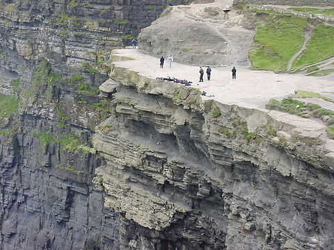 Carefully enjoying the cliffside view These people exercise extreme caution and with good reason. If you slip here, you fall about 214 meters down.This picture is taken at the Cliffs of Moher, Ireland Cliffs of Moher,Europe,Ireland