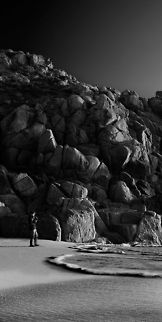 Cracked_Granite_at_Porthcurno,_Cornwall This was taken at Porthcurno in Cornwall. This is quite a spectacular area of the coast with particularly rugged features. I wanted to capture the beautiful shapes in the rock, which have been weathered and cracked over time (this is why I opted for side-lighting). I included a person in the shot to give it a sense of scale. The lighting and tones in the sky meant that this converted really nicely to black and white. To maximize resolution, I took a succession of images vertically and stitched them together in Photoshop. My shutter speed was slow (1/20) to blur the movement of the person and water, but I maintained a narrow aperture for sharpness.  Black and white,Cliffs,Coastal,Cornwall,Cracks,Geology,Granite,Huge,Landscape,Mountain,Porthcurno,Sennen