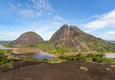 Cerros de Mavecure, Inírida, Colombia This unique geological scene is a two hour boat fare away from the Inírida port. On this day, we were the first to arrive, having it all to ourselves. The site is bizarre and consists of 3 mountains that seem to appear out of nowhere in a surrounding environment that is almost entirely flat for hundreds of miles.

We had to climb up on the other side to get this overview shot, which shows on the left the mountain Mono (Monkey, 480m) and on the right Pajarito (Little Bird, 712m).

Ground level panorama:
https://www.jungledragon.com/image/53280/cerros_de_mavecure_-_ground_level_inrida_colombia.html

Behind us:
https://www.jungledragon.com/image/53282/cerros_de_mavecure_-_opposite_side_inrida_colombia.html

Foggy top of "Little Bird":
https://www.jungledragon.com/image/53283/cerros_de_mavecure_-_cerro_pajarito_inrida_colombia.html
https://www.jungledragon.com/image/53284/cerros_de_mavecure_-_cerro_pajarito_foggy_inrida_colombia.html

"Monkey" from ground level:
https://www.jungledragon.com/image/53285/cerros_de_mavecure_-_cerro_mono_inrida_colombia.html
https://www.jungledragon.com/image/53287/cerros_de_mavecure_-_cerro_mono_inrida_colombia.html

"Monkey" from water:
https://www.jungledragon.com/image/53288/cerros_de_mavecure_-_cerro_mono_from_water_inrida_colombia.html

Another ground level panorama:
https://www.jungledragon.com/image/53286/cerros_de_mavecure_-_cerro_mono_and_cerro_pajarito_inrida_colombia.html

Size reference:
https://www.jungledragon.com/image/53289/cerros_de_mavecure_-_size_reference_inrida_colombia.html Colombia,Guainía,Inírida,South America,World