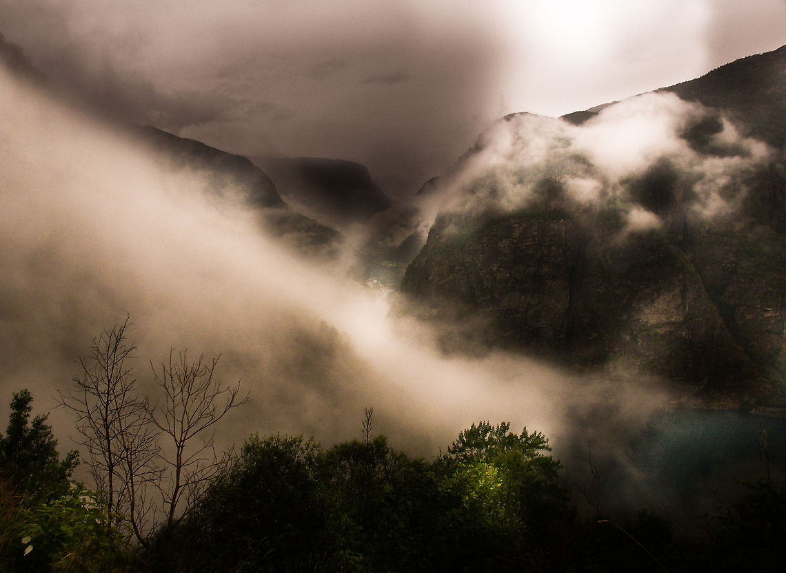 Glimpse of Valhalla I remember it well. <br />
<br />
We walked a mountain path in greyish thunderous weather. We would get wet to the bone.<br />
Suddenly a few strands of light break through the clouds and turn the landscape dappled in myth for half a minute. Clouds of legend!<br />
<br />
Then the moment was gone, yet etched into our minds. <br />
Was it a glimpse of Valhalla? Geotagged,Norway,dark,fjord,mist,myth