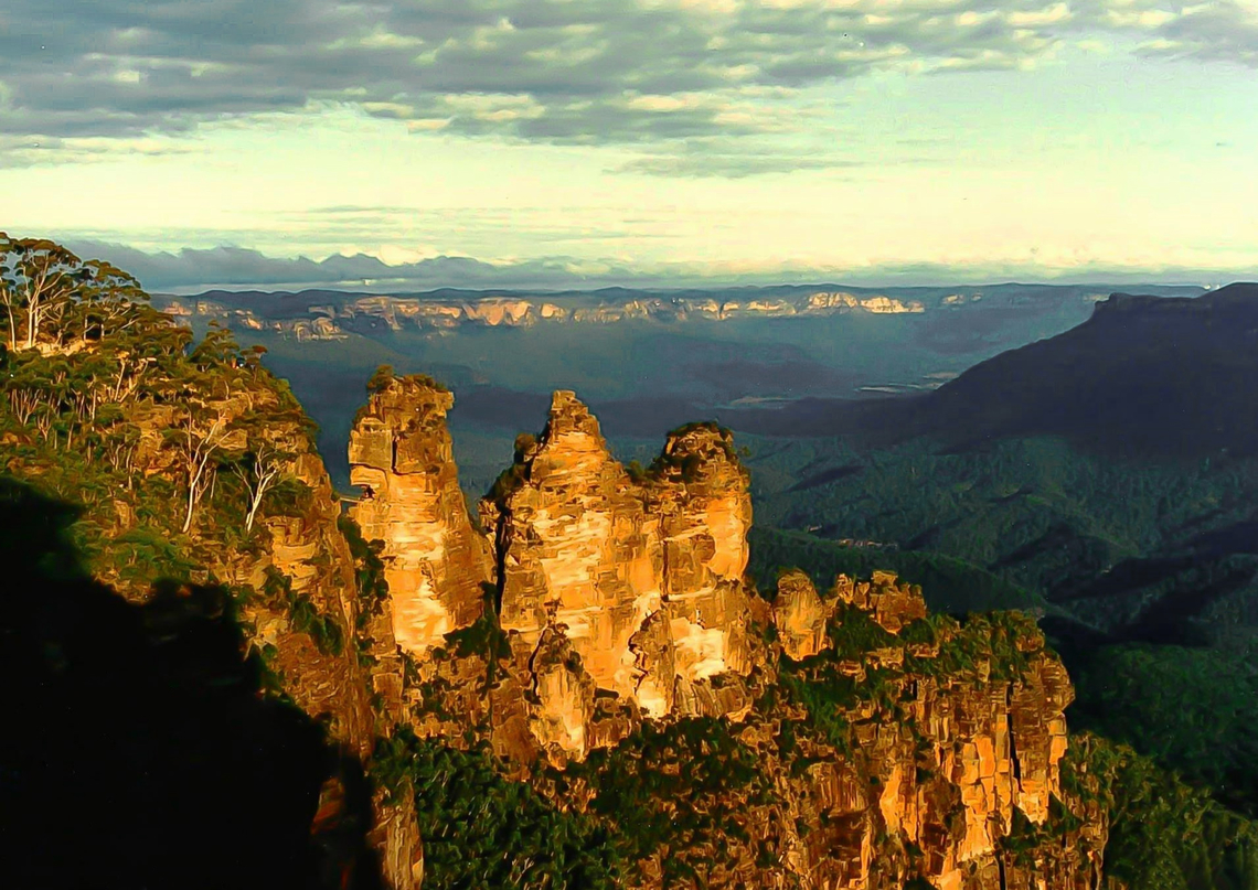 Three Sisters Jamison Valley These rock formations are made of sandstone, like the walls of the surrounding Jamison Valley. The three formations were created by wind and rain which is constantly sculpting the soft sandstone of the Blue Mountains. The three sisters can be seen from Echo Point lookout. <br />
<br />
A commonly told legend of Our First Nations people tells the tale of three sisters &#039;Meehni&#039;, &#039;Wimlah&#039; and Gunnedoo&#039;. These three girls were part of the Katoomba tribe. All three fell in love with men from the Nepean tribe; however laws forbade the girls from following their desires and marrying outside their own people. A major tribal battle ensued, and the sisters were turned to stone by an elder to protect them. <br />
<br />
<br />
The site has UNESCO world heritage listing. Australia,Australian landscape,Blue Mountains,Geotagged,Jamison Valley,Katoomba,New South Wales,Summer,Three Sisters,sandstone rock fomations,wild landscape