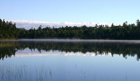 Astrid Lake in the early morning. Astrid Lake is a very clear lake about 57 acres in size with non-mineralized (soft) water. Surrounding forests are primarily a mixture of pines, spruce, fir, and aspen but pin oak and red maple are also common in places. The substrate is sand and gravel derived from regional gneiss bedrock. The lake is accessible by a footpath which continues past it into the pine forests on the other side. Astrid Lake,Geotagged,Minnesota,Summer,United States,early morning,lake,water