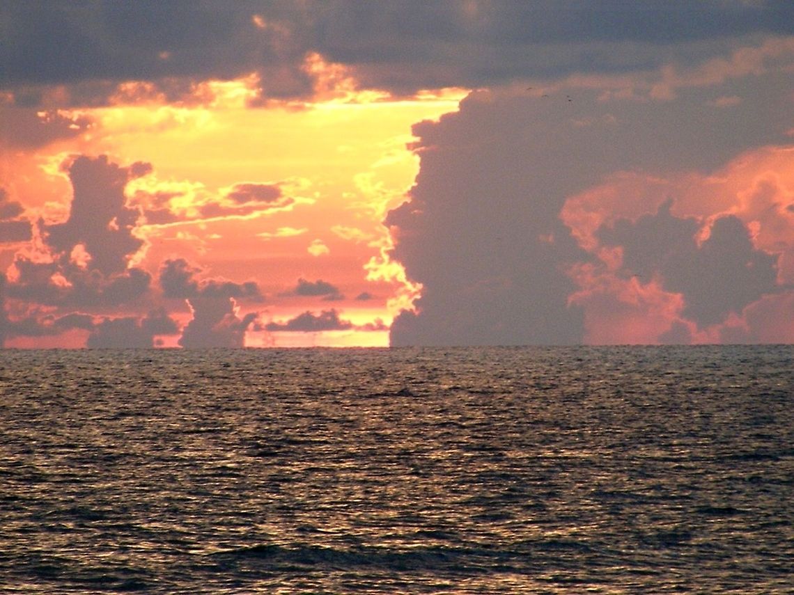 Sunset over the water The time of sunset is defined in astronomy as the moment when the trailing edge of the Sun's disk disappears below the horizon in the west. The ray path of light from the setting Sun is highly distorted near the horizon because of atmospheric refraction, making the sunset appear to occur when the Sun refraction,sunset