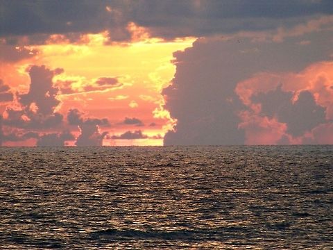 Sunset over the water The time of sunset is defined in astronomy as the moment when the trailing edge of the Sun's disk disappears below the horizon in the west. The ray path of light from the setting Sun is highly distorted near the horizon because of atmospheric refraction, making the sunset appear to occur when the Sun refraction,sunset