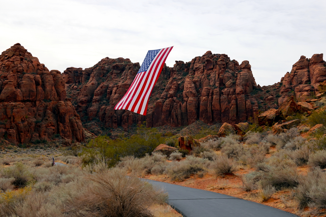 Snow Canyon St. George Utah "Follow the Flag" Surrounded by unique red sand stone cliffs and with all state permissions granted, this organization flies the United States flag around the western Unites States. It weighs 400 lbs and takes a team of people to move it it around. This flag is 150&rsquo;x78&prime; feet! A total of 11,700 square feet. The red and white stripes alone are six feet thick. This is the largest American flag to ever fly.<br />
They use a light weight but very strong Kelvar cable stretched across the red sand stone canyon peaks to position the flag.<br />
5N4A7694-1 Fall,Geotagged,United States