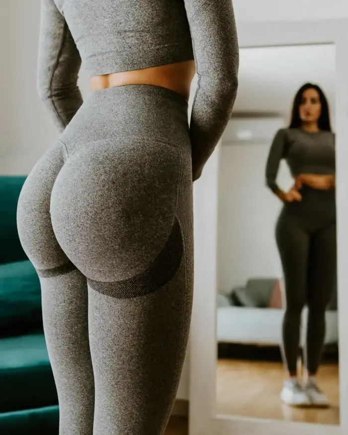 Woman standing in front of mirror with butt in focus