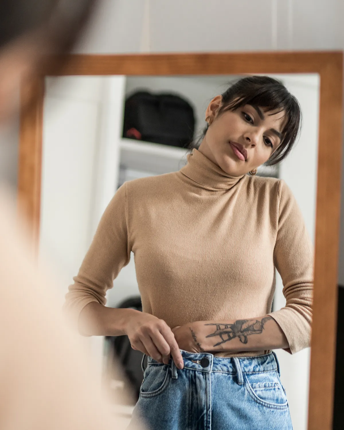 Woman looking in mirror and trying on clothes