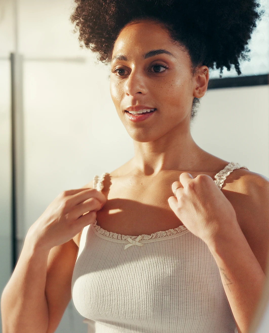 Woman fixing shirt in mirror