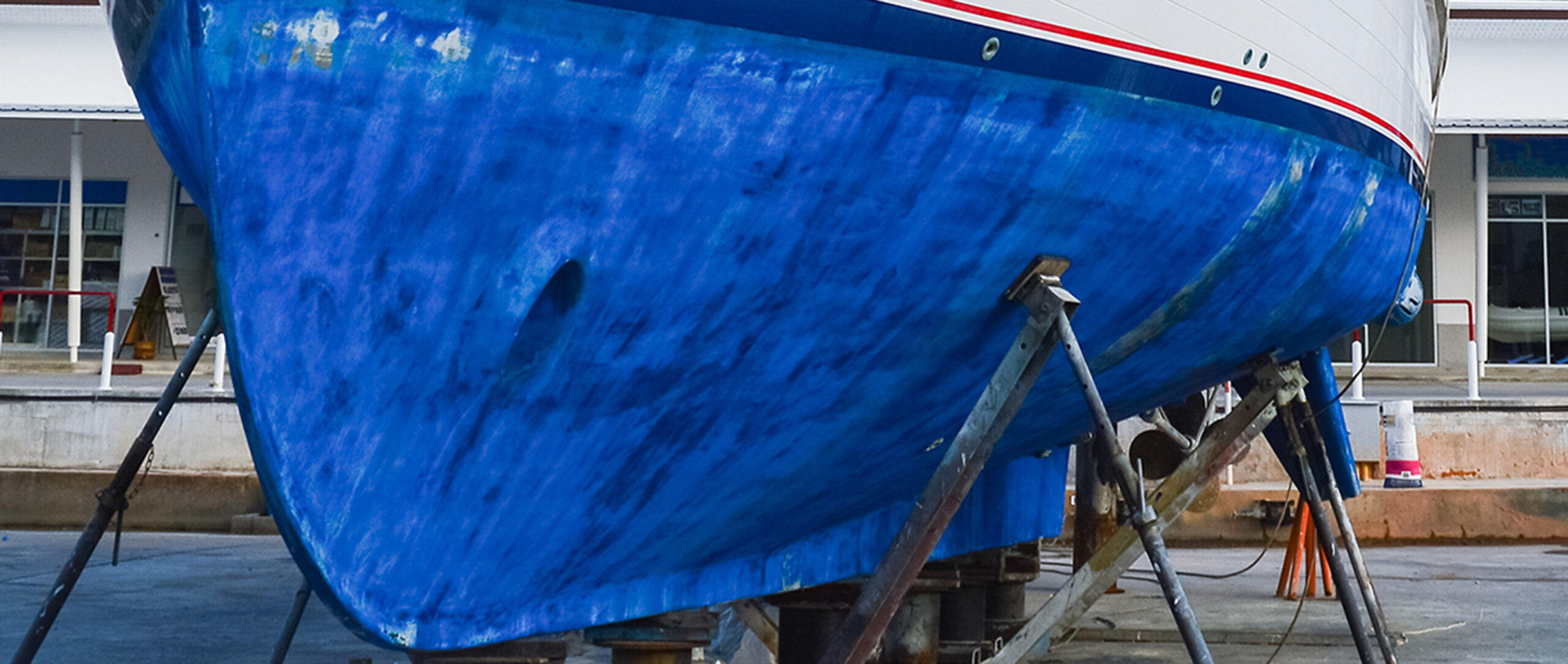 The varnished and highly polished hull of a single masted yacht sitting on stocks at Arisaig marina undergoing repair and maintenance.