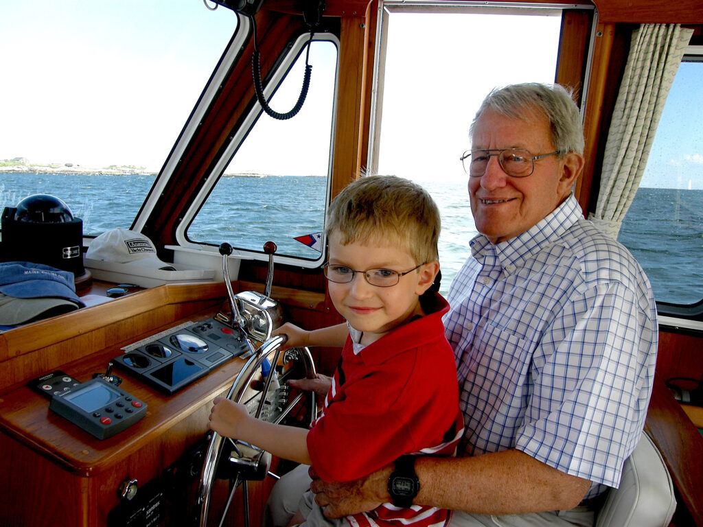 Old man you a young boy. on his lap a driving a yacht.