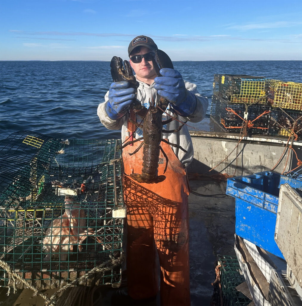 Young man holding a lobster on a boat.