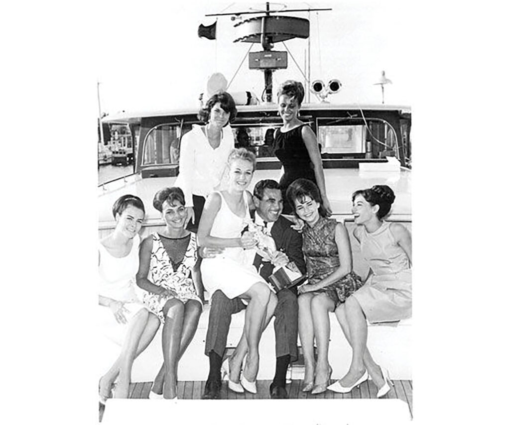 Don Aronow posing with seven women on a boat