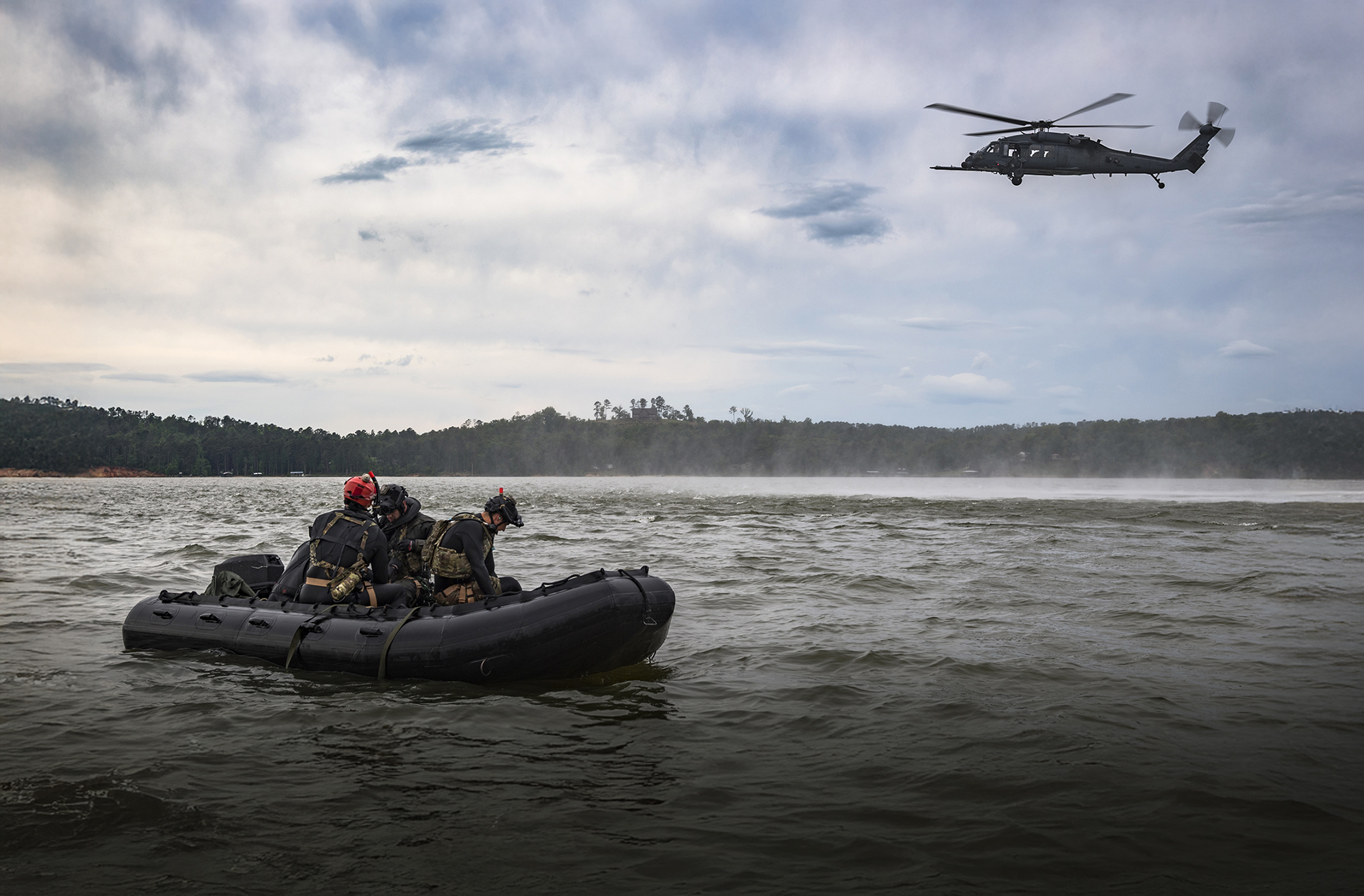 Soldiers in a RIB with a helicopter hovering overhead