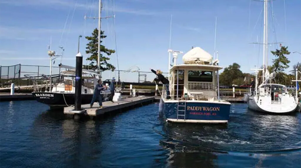 Woman on a boat heaving a line to a man on a dock.