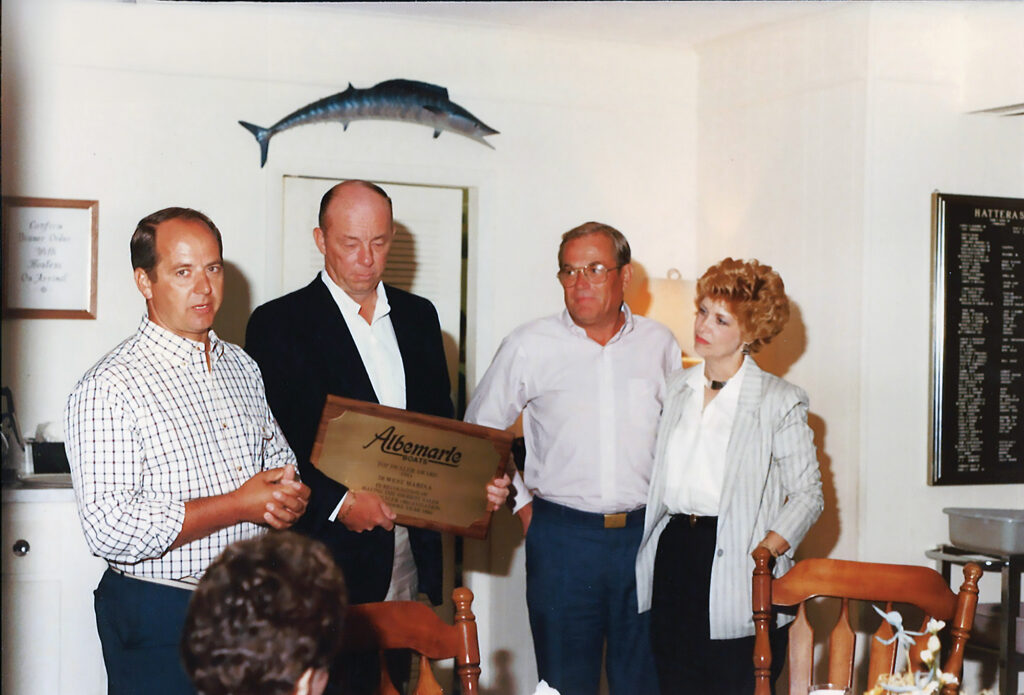 Three men and a woman posing with a plaque