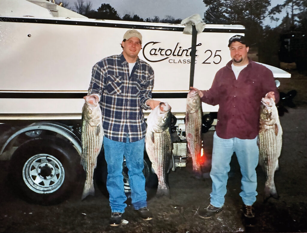 Two men posing with striped bass