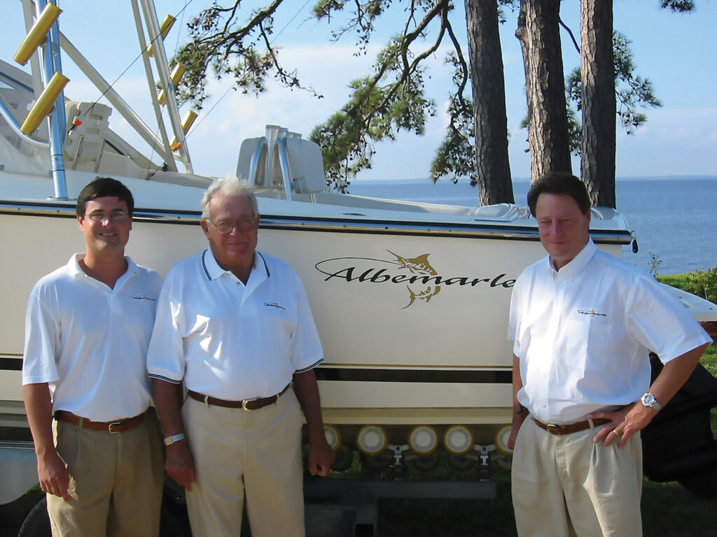 Three men posing next to a boat