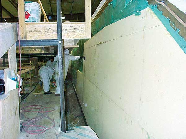 Core material, with closely spaced bleeder holes (not visible) drilled through, is primed with resin and stuck into the putty before the vacuum bag (rolled up, above workmen) is applied.