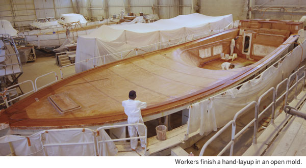 Workers finish a hand-layup in an open mold.