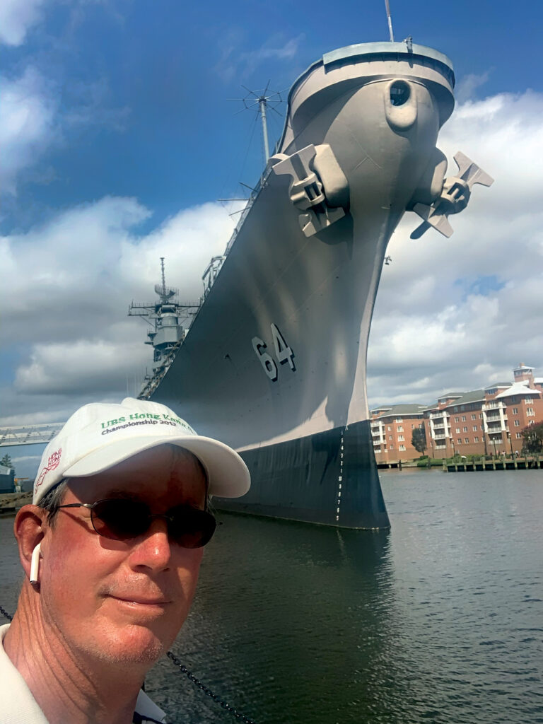 a man taking a selfie in front of a large ship
