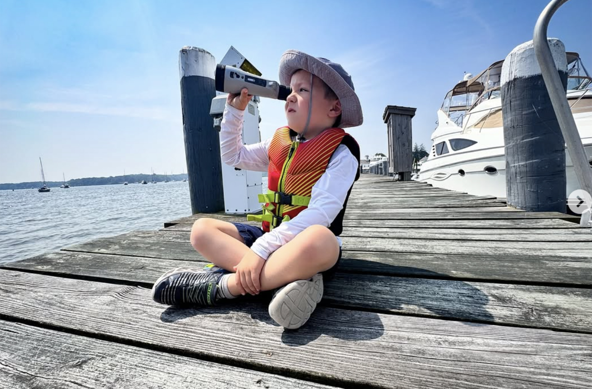 Child on a dock looking through a telescope