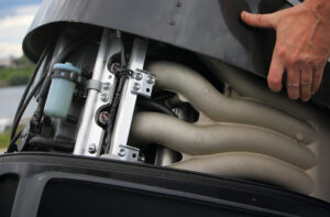 A man's hand open the hood of a powerful boat outboard motor