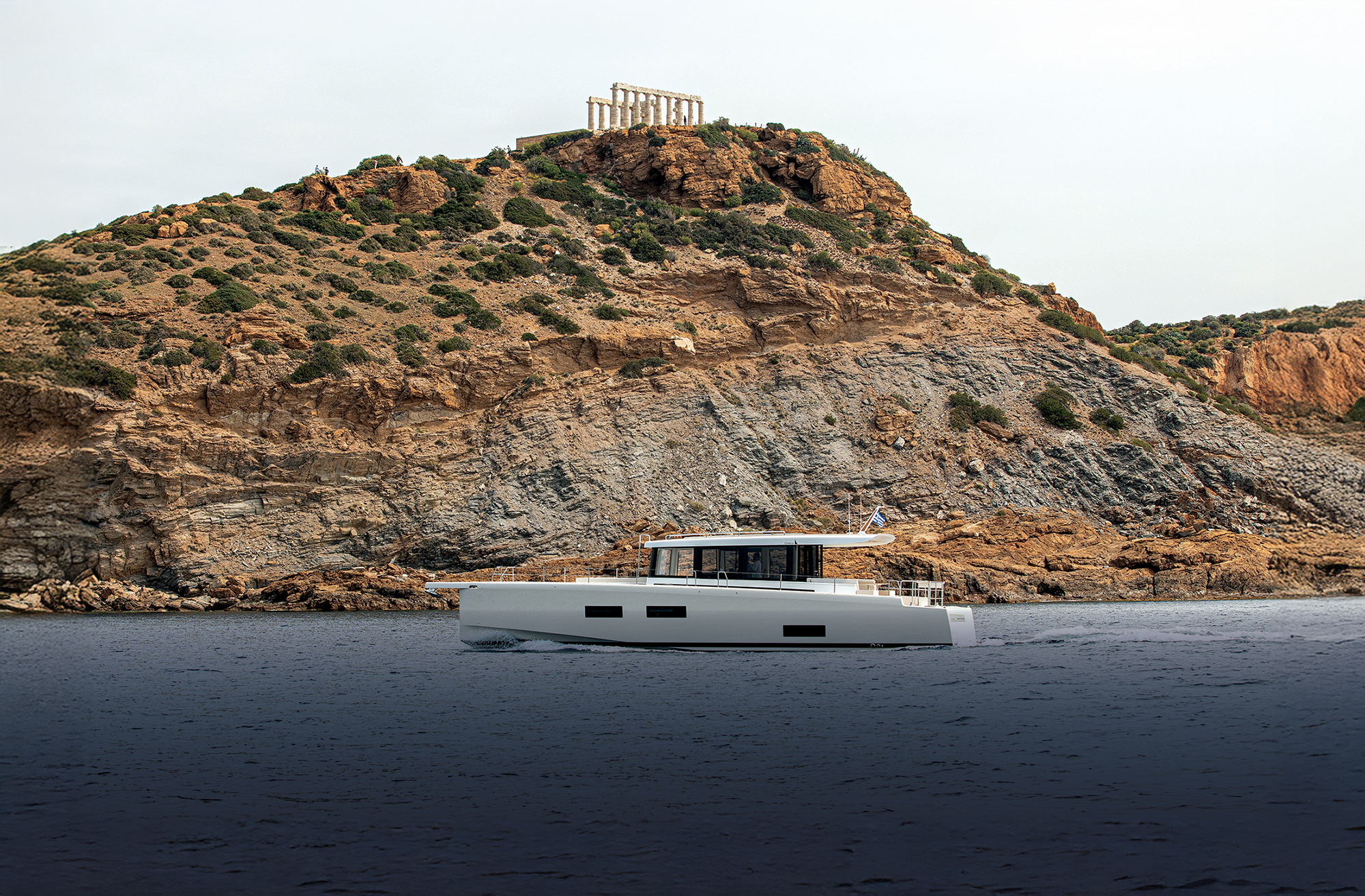 Yacht with Greek ruins on a hill in the background