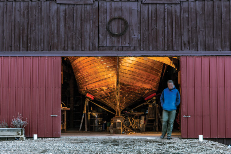 Man in front of a barn with a boat in it
