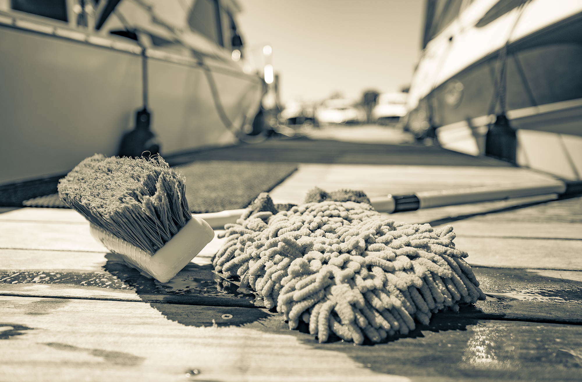 Mop and brush on a dock with boats in the background