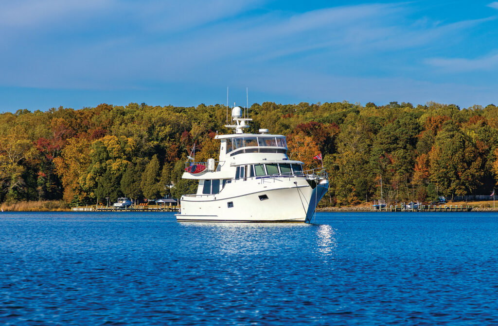 White yacht on blue water with green trees in the background