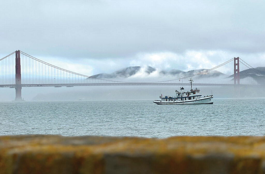 A classic boat in fog with the Golden Gate bridge in the background