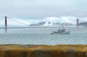 A classic boat in fog with the Golden Gate bridge in the background