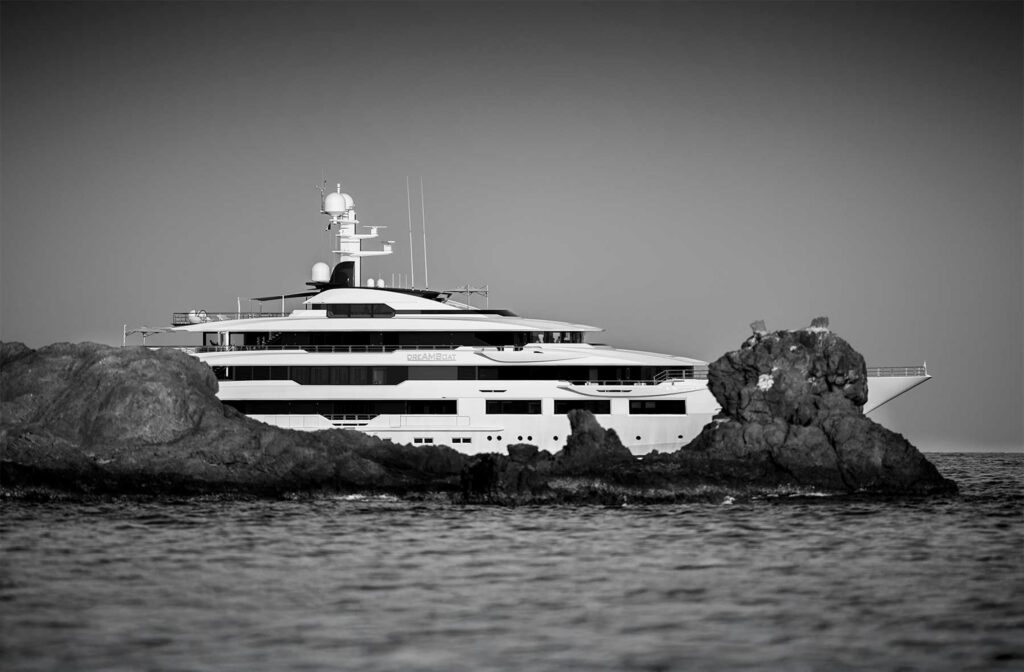 Large yacht partially seen behind rocks